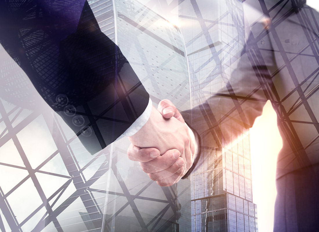 Commercial Insurance - Closeup Digitalized Image with Two Businessmen Shaking Hands Against Tall Building Backdrop and Lens Flare