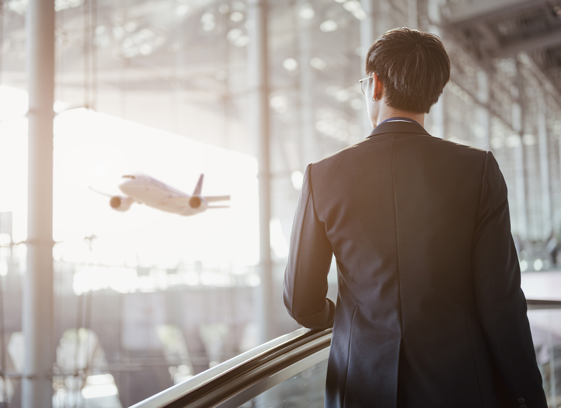 International Business - Man at Airport Looking Out a Plane Taking Off for Flight