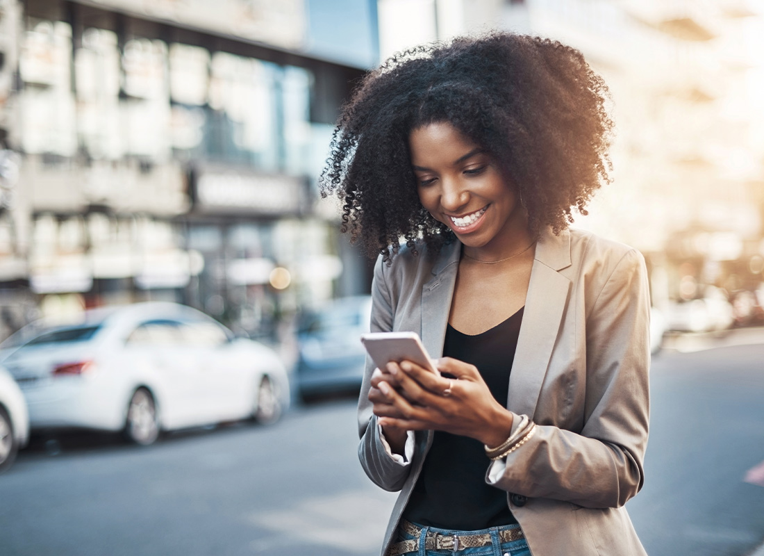 Read Our Reviews - Smiling Young Businesswoman Using a Cellphone in the City